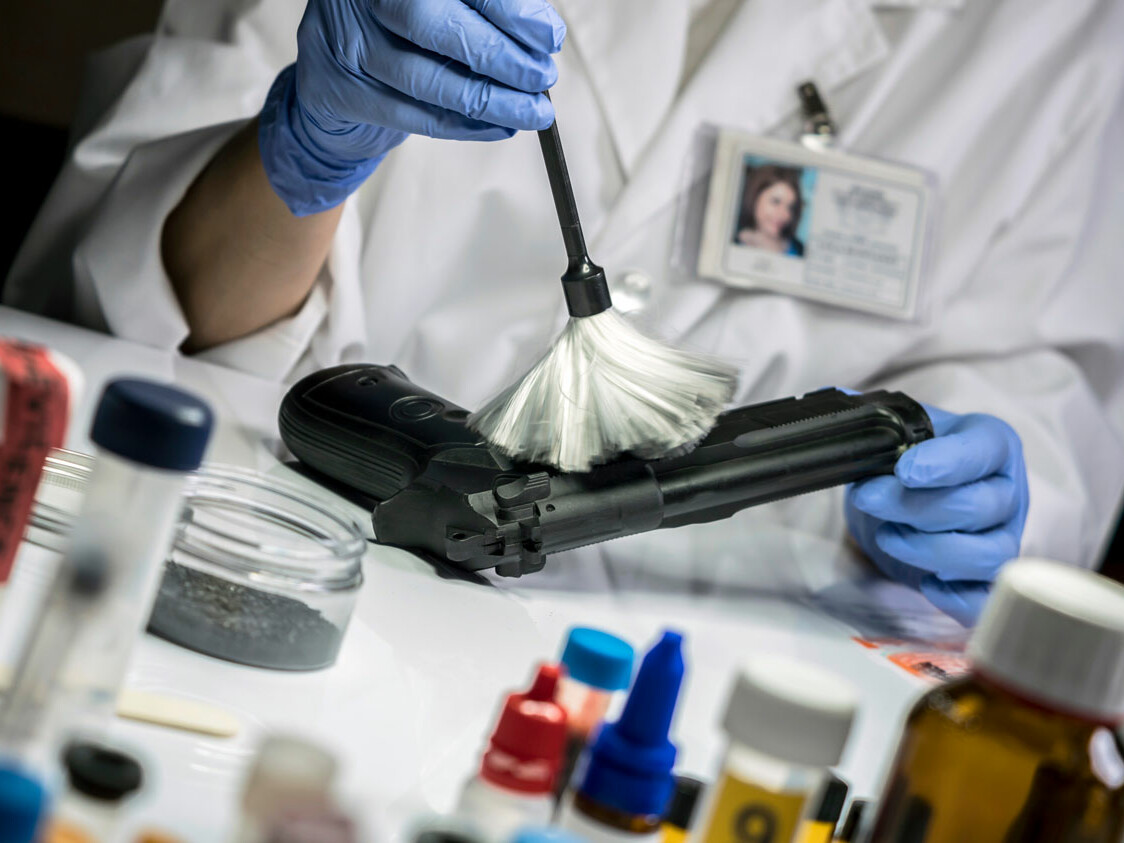 Crime laboratory close up of gun being brushed for fingerprints